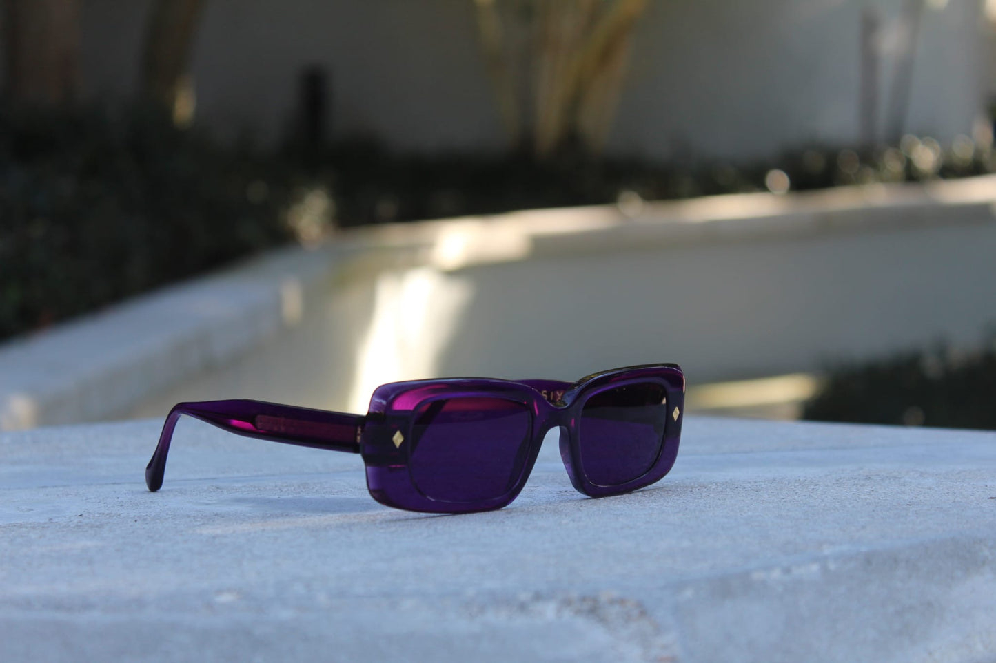 “Purple Gift sunglasses by Cloud Jelly resting on a white stone surface, capturing modern elegance in soft lighting”