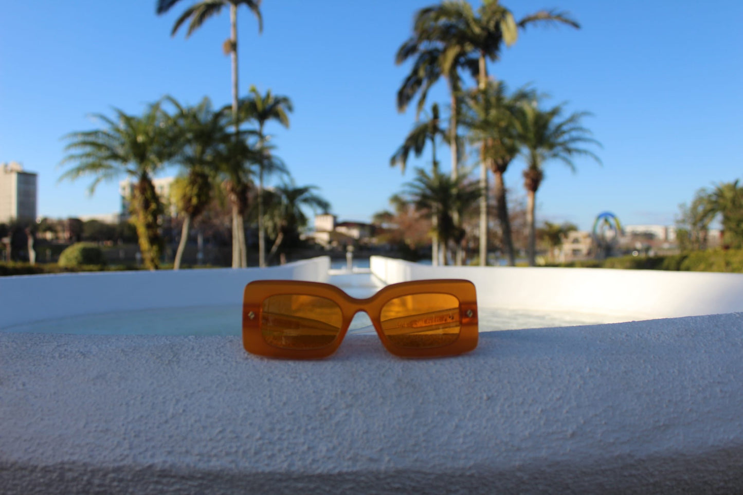 “Sun sunglasses by Cloud Jelly on tropical background, showcasing their trendy Orange design”