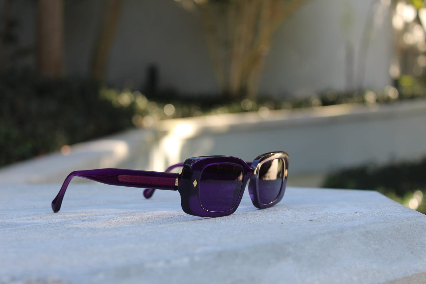 “Purple Gift sunglasses by Cloud Jelly resting on a white stone surface, capturing modern elegance in soft lighting”